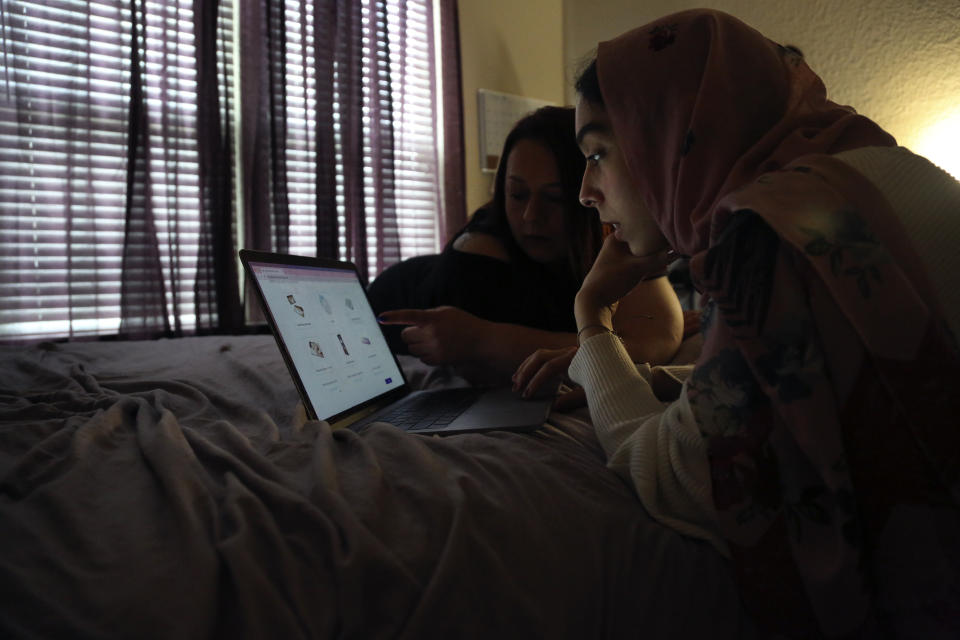 Angela Ahmed, left, and her daughter, Amirah Ahmed, 17, lay on a bed while browsing the internet on Saturday, Aug. 14, 2021, in Fredericksburg, Va. (AP Photo/Jessie Wardarski)