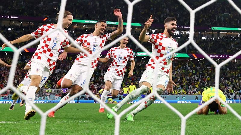 Josko Gvardiol, Ante Budimir, Dejan Lovren y Lovro Majer de Croacia celebran la clasificación para las semifinales mientras Marquinhos de Brasil luce abatido tras fallar un penal y ser eliminado de la Copa del Mundo, en el Education City Stadium, Doha, Qatar