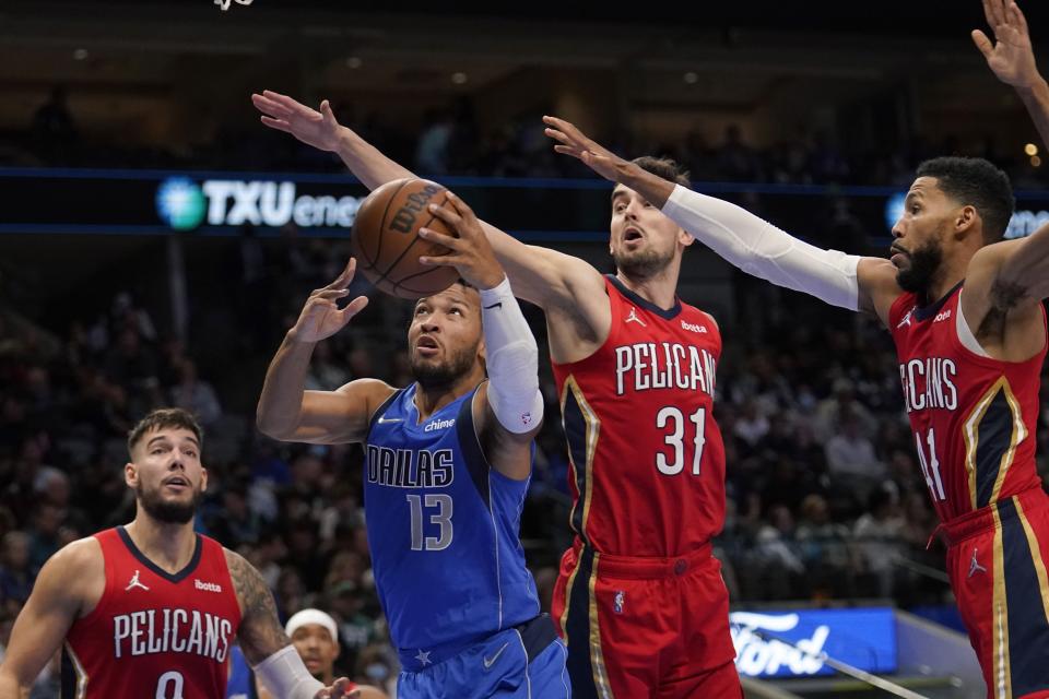 Dallas Mavericks guard Jalen Brunson (13) leaps to the basket to shoot as New Orleans Pelicans' Willy Hernangomez, left, Tomas Satoransky (31) and Garrett Temple (41) defend in the second half of an NBA basketball game in Dallas, Friday, Dec. 3, 2021. (AP Photo/Tony Gutierrez)