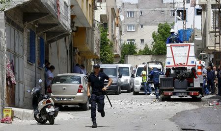 A riot police officer runs away from the site after two rockets hit the Turkish town of Kilis near the Syrian border, Turkey, April 24, 2016. REUTERS/Umit Bektas