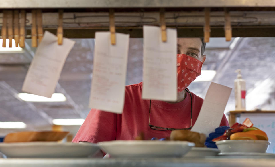 PORTLAND, ME - APRIL 15: Waitress Millie Norton checks an order clipped to a clothespin between her and the line cooks during breakfast service at Beckys Diner in Portland on Thursday, April 15, 2021. Norton was working a position called The Expeditor, created when the diner reopened for service during the pandemic to alleviate waitress crowding in the area. The wait staff rotates through the position, which ensures orders are plated correctly, makes toast and adds condiments to the plates. (Staff photo by Gregory Rec/Portland Press Herald via Getty Images)