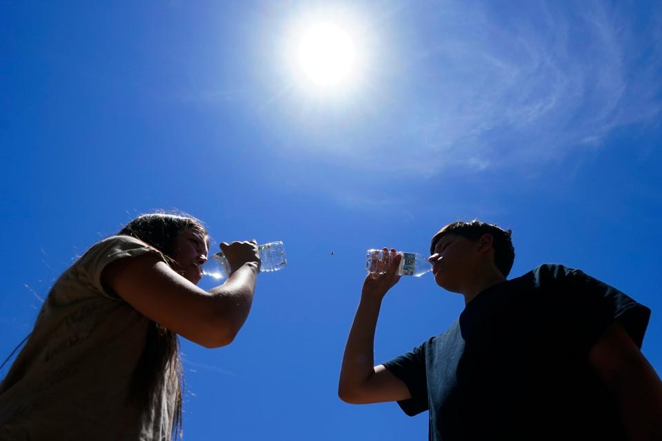 Tony Berastegui Jr., 15, right, and his sister Giselle Berastegui, 12, drink water as temperatures are expected to hit 115-degrees on July 17, 2023, in Phoenix.
