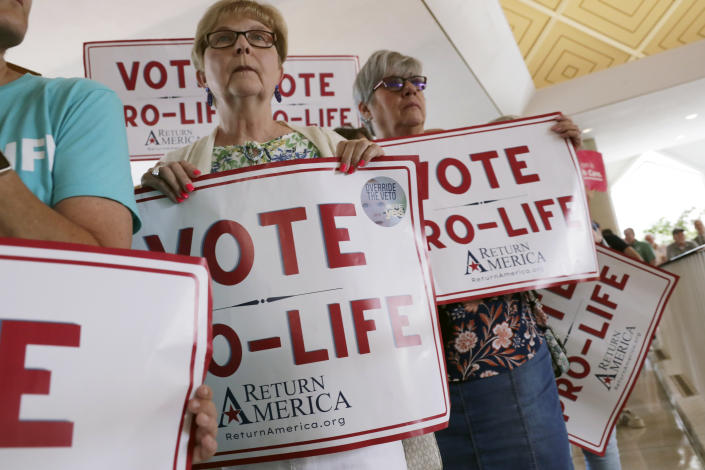 Anti-abortion supporters hold signs, Tuesday, May 16, 2023, in Raleigh, N.C., as they wait to enter the Senate gallery as state legislators debate on whether to override Democratic Gov. Roy Cooper's veto of a bill that would change the state's ban on nearly all abortions from those after 20 weeks of pregnancy to those after 12 weeks of pregnancy. Both the Senate and House had to complete successful override votes for the measure to be enacted into law. The Senate voted to override the veto. (AP Photo/Chris Seward)