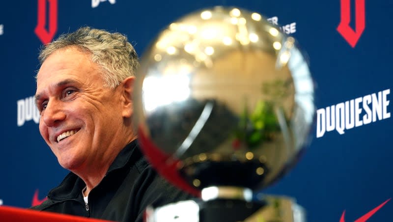 Duquesne University men's basketball coach Keith Dambrot sits next to the Atlantic 10 championship trophy during a gathering in Pittsburgh celebrating Duquesne earning a berth in the NCAA Tournament for the first time since 1977 Monday, March 18, 2024. Dambrot announced that he is retiring after his team's NCAA tournament run.