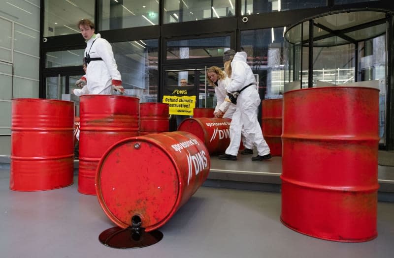Greenpeace activists protest against investment policy of the DWS Investment's with red oil drums in front of the company's headquarters in Frankfurt. Boris Roessler/dpa