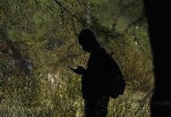 A migrant checks his cellphone at an improvised refugee camp at a sport park in Ciudad Acuña, Mexico, Wednesday, Sept. 22, 2021. (AP Photo/Fernando Llano)