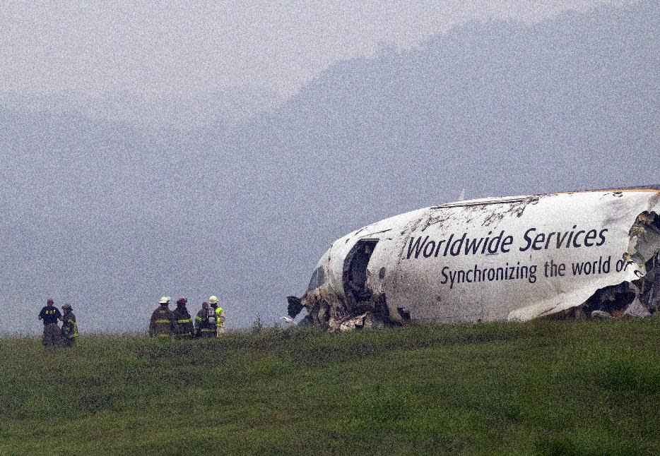 FILE - In this Aug. 14, 2013, file photo, fire crews work the scene of a UPS cargo plane crash at the Birmingham-Shuttlesworth International airport in Birmingham, Ala. Federal investigators are looking at pilot fatigue, among other issues, as a possible factor in the fatal predawn crash of a UPS cargo jet. The National Transportation Safety Board scheduled a hearing for Feb. 20, 2014, on the accident, which killed both pilots.(AP Photo/Butch Dill, File)