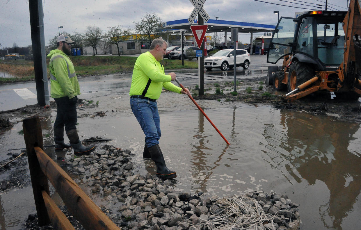 Wooster city employees Dick Troyer and Randy Johnson earlier this month try to locate a plugged pipe at the bottom of an 8-foot deep ditch on West Old Lincolnway by the fairgrounds so they can unplug it with the backhoe. The National Weather Service forecasts a severe storm for this afternoon.