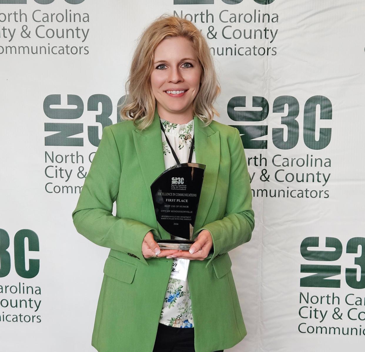 City of Hendersonville Communications Coordinator Brandy Heatherly poses with her NC3C communicators conference "Best of Humor" award she won for her April Fool's social media post where firefighters were using pool noodles instead of hoses to put out fires.
