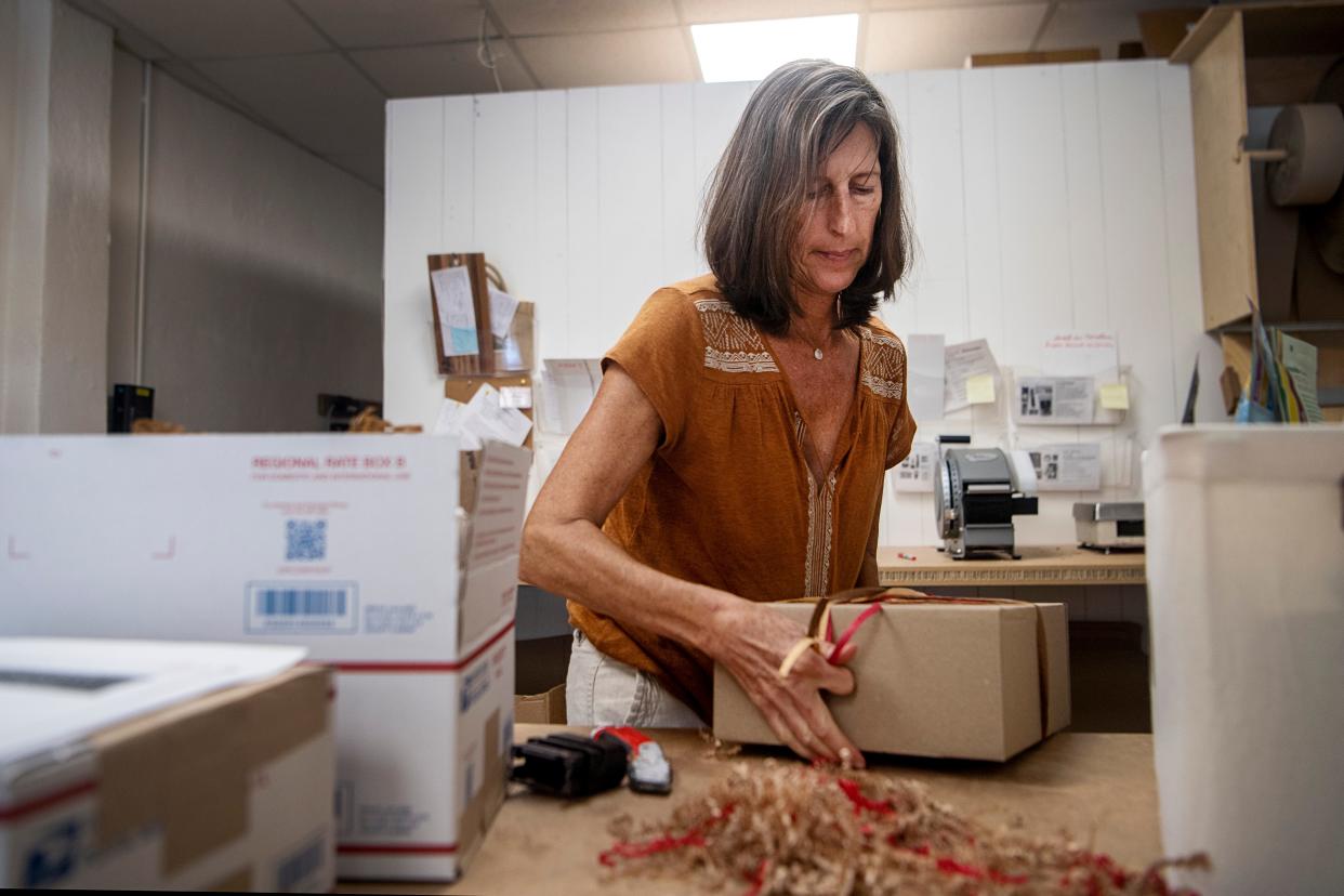 Celia Naranjo, owner of the West Asheville gift basket store Asheville Goods, ties a bow on a box August 17, 2023.