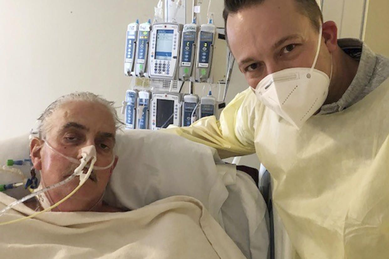 David Bennett Jr., right, stands next to his father's hospital bed in Baltimore on Jan. 12, five days after doctors transplanted a pig heart into Bennett in an effort to save his life.   (University of Maryland School of Medicine via AP)