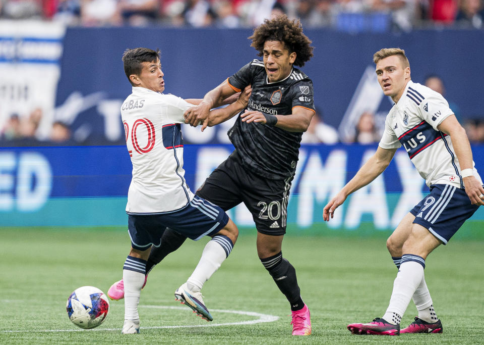 Houston Dynamo's Coco Carrasquilla, center, tries to fight past Vancouver Whitecaps' Andres Cubas, left, as Julian Gressel looks on during the first half of an MLS soccer match in Vancouver, British Columbia, Wednesday, May 31, 2023. (Rich Lam/The Canadian Press via AP)