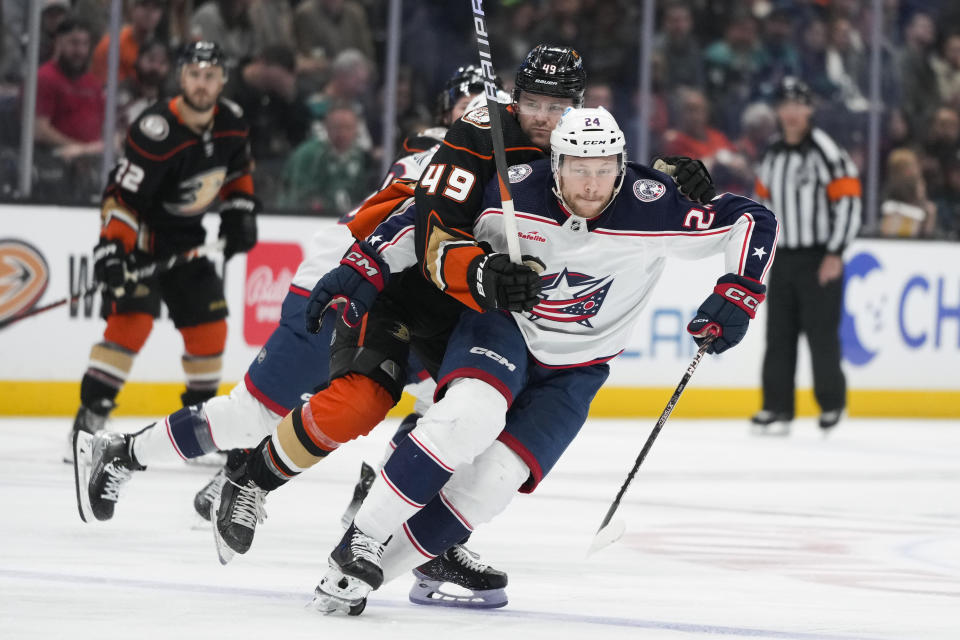 Columbus Blue Jackets' Mathieu Olivier (24) and Anaheim Ducks' Max Jones (49) chase the puck during the first period of an NHL hockey game Friday, March 17, 2023, in Anaheim, Calif. (AP Photo/Jae C. Hong)