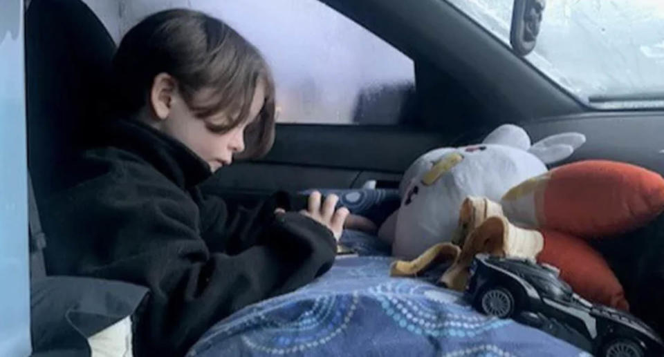 Charlie sitting in the front seat of his mum's ute after they became homeless.