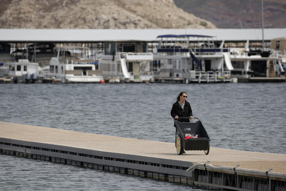 FILE - In this Monday, March 23, 2020, file photo, a woman removes items before the Las Vegas Boat Harbor closes at the Lake Mead National Recreation Area near Boulder City, Nev. As the coronavirus pandemic continues, the National Park Service is testing public access at several parks across the nation, including Nevada, with limited offerings and services. (AP Photo/John Locher, File)