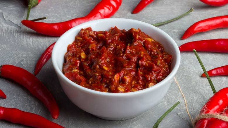 Bowl of harissa next to chili peppers