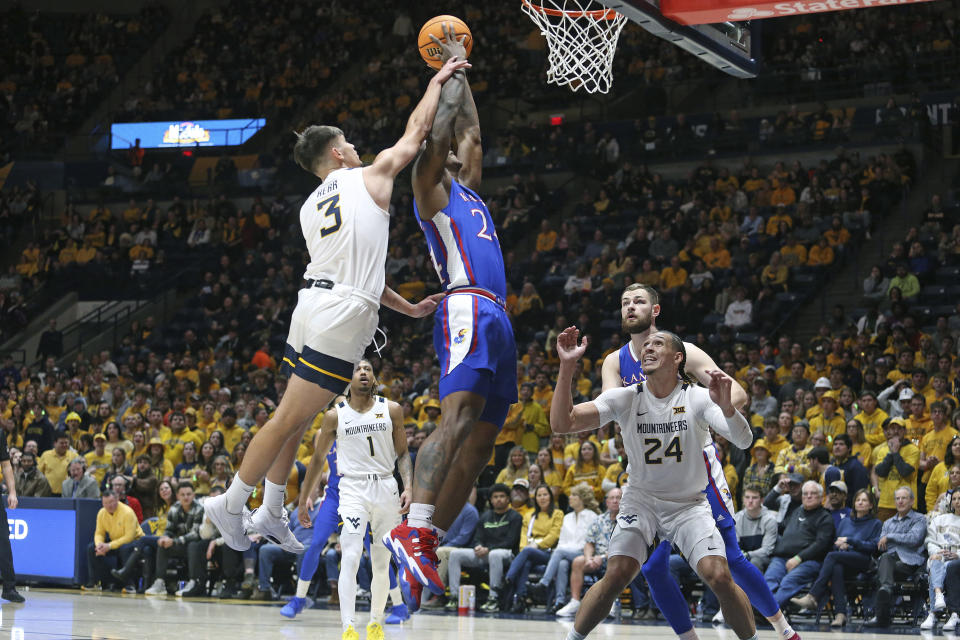 Kansas forward K.J. Adams Jr. (24) shoots while defended by West Virginia guard Kerr Kriisa (3) and forward Patrick Suemnick (24) during the first half of an NCAA college basketball game on Saturday, Jan. 20, 2024, in Morgantown, W.Va. (AP Photo/Kathleen Batten)