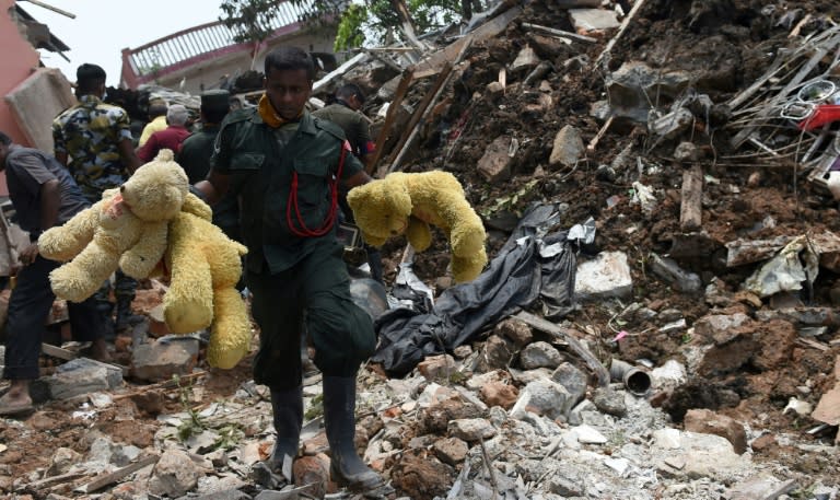 Sri Lankan army soldiers walk past damaged houses after the collapse of a garbage dump in Meetotamulla, on the outskirts of Colombo