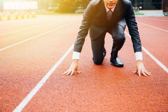 Businessman in the starting position on an Olympic-style running track.