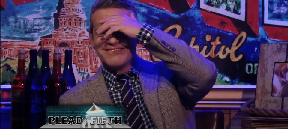 Andy Cohen blushes with a hand over his face