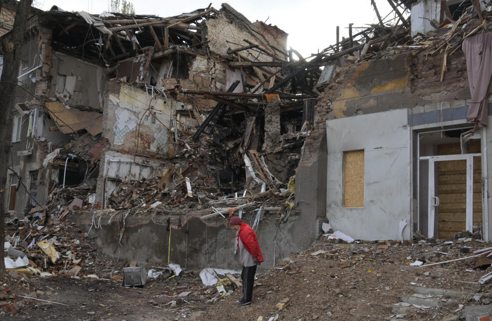 Local resident Nina, 72, stands near her house, ruined by the Russian shelling a month ago in central Slavyansk, Donetsk region, Ukraine, Saturday, Oct. 29, 2022. She keeps living in this house and collects wooden debris to make an outdoor fire for cooking. (AP Photo/Efrem Lukatsky)