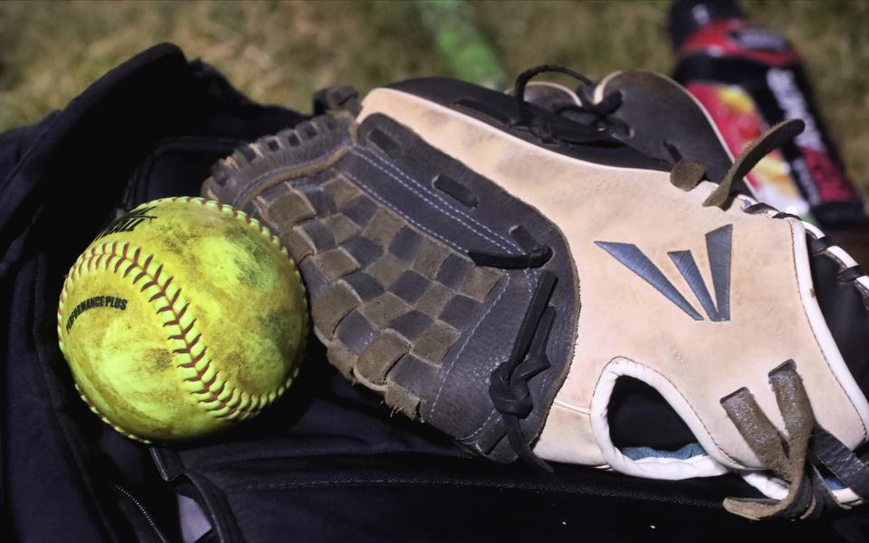 A softball and a glove rest on a backpack as they team warm up for a softball game at McKnight Park on Tuesday, Sept. 5, 2023.