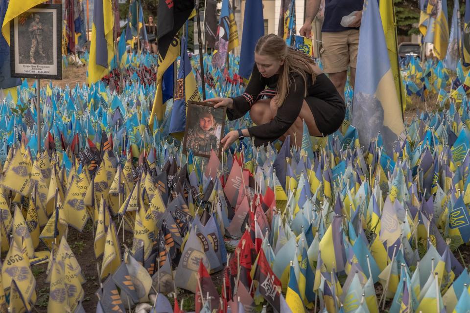 A woman displays a portrait of a Ukrainian army serviceman at a memorial area with Ukrainian and other countries flags commemorating fallen Ukrainian and foreign fighters at the Independence Square, in Kyiv (AFP via Getty Images)