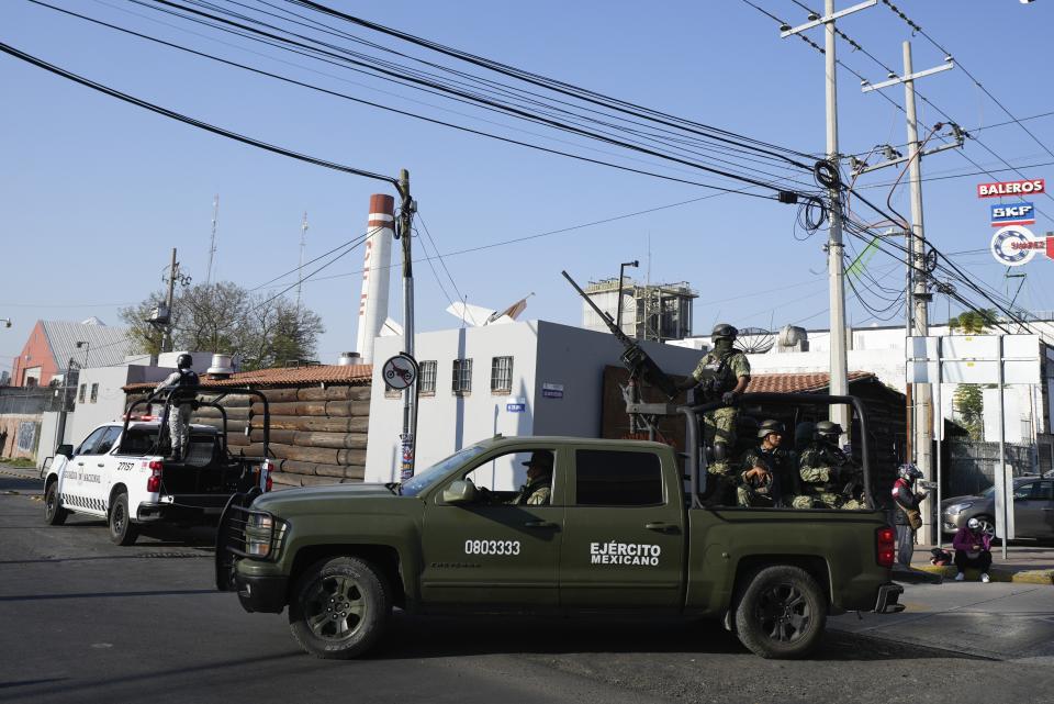 Mexican Army soldiers drive past a crime scene where a municipal police officer was shot dead, in a neighborhood of Celaya, Guanajuato state, Mexico, Wednesday, Feb. 28, 2024. In Guanajuato state, more police were shot to death in 2023 than across the United States. (AP Photo/Fernando Llano)