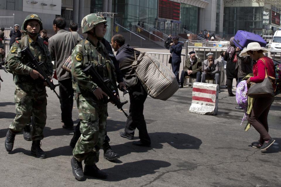 Heavily armed Chinese paramilitary policemen march past the site of the Wednesday's explosion outside the Urumqi South Railway Station in Urumqi in northwest China's Xinjiang Uygur Autonomous Region Thursday, May 1, 2014. Chinese President Xi Jinping has demanded "decisive actions" against terrorism following an attack at the railway station in the far-west minority region of Xinjiang that left three people dead and 79 injured. (AP Photo/Ng Han Guan)