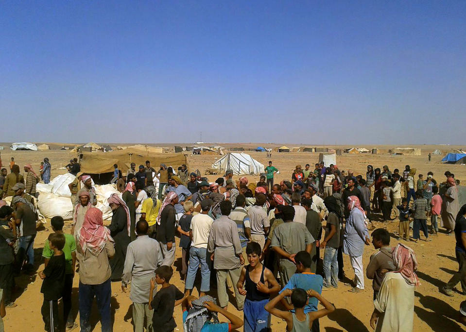 FILE - In this Aug. 4, 2016 file photo, displaced people wait to receive aid at the Rukban camp, near the Jordan-Syria border. The U.S. military said Monday, April, 8, 2019 that it is not preventing Syrians from leaving the remote Rukban camp near an American base in Syria and is urging Russia and Damascus to help facilitate the delivery of humanitarian aid. Russia has recently called for the camp to be dismantled and accused the U.S. of hindering such efforts. (AP Photo, File)