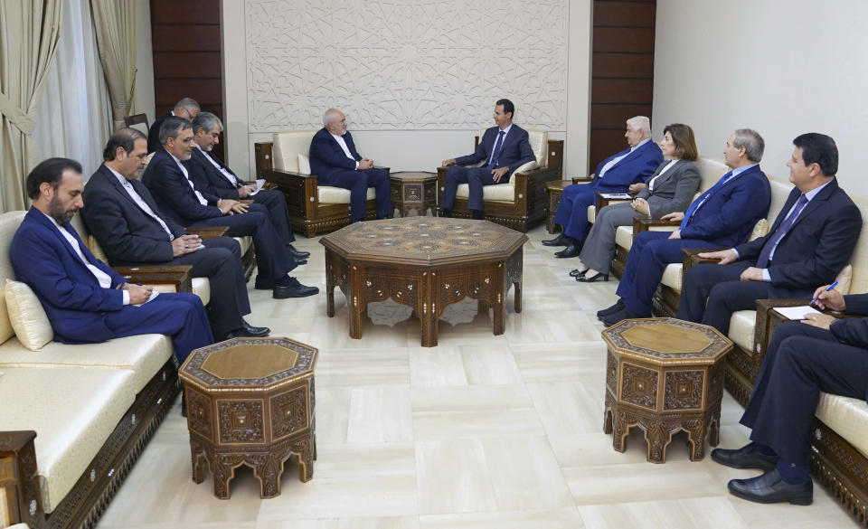 In this photo released by the Syrian official news agency SANA, Syrian President Bashar Assad, center right, meets with Iranian Foreign Minister Mohammad Javad Zarif in Damascus, Syria, Monday, Sept 3, 2018. Zarif said at the start of a visit to Damascus on Monday that "terrorists must be purged" from Syria's Idlib and the entire northwestern province returned to government control. (SANA via AP)
