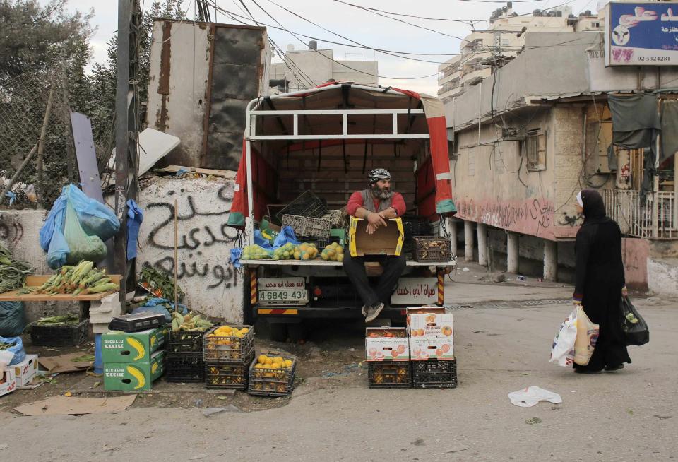 A Palestinian vendor sells fruits and vegetables from the back of a van in the Shuafat refugee camp in the West Bank near Jerusalem