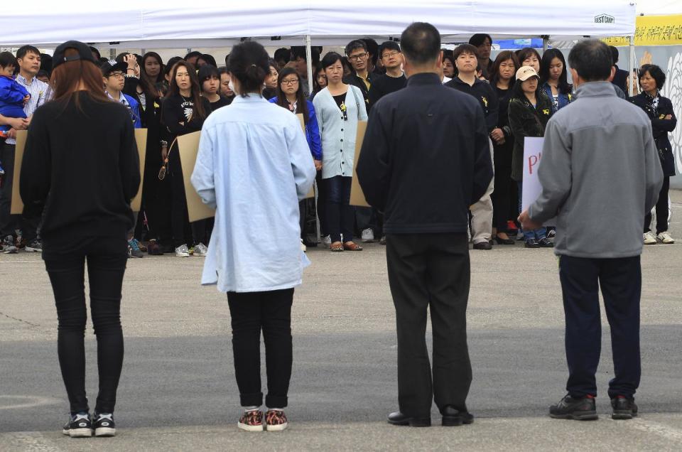 Family members of passengers aboard the sunken ferry Sewol stand to protest delays in the search operation as people wait to pay tribute to the victims of the ship at a group memorial altar in Ansan, South Korea, Sunday, May 4, 2014. South Korean President Park Geun-hye told families of those missing in the sunken ferry that her heart breaks knowing what they are going through, as divers recovered two more bodies on Sunday. (AP Photo/Ahn Young-joon)