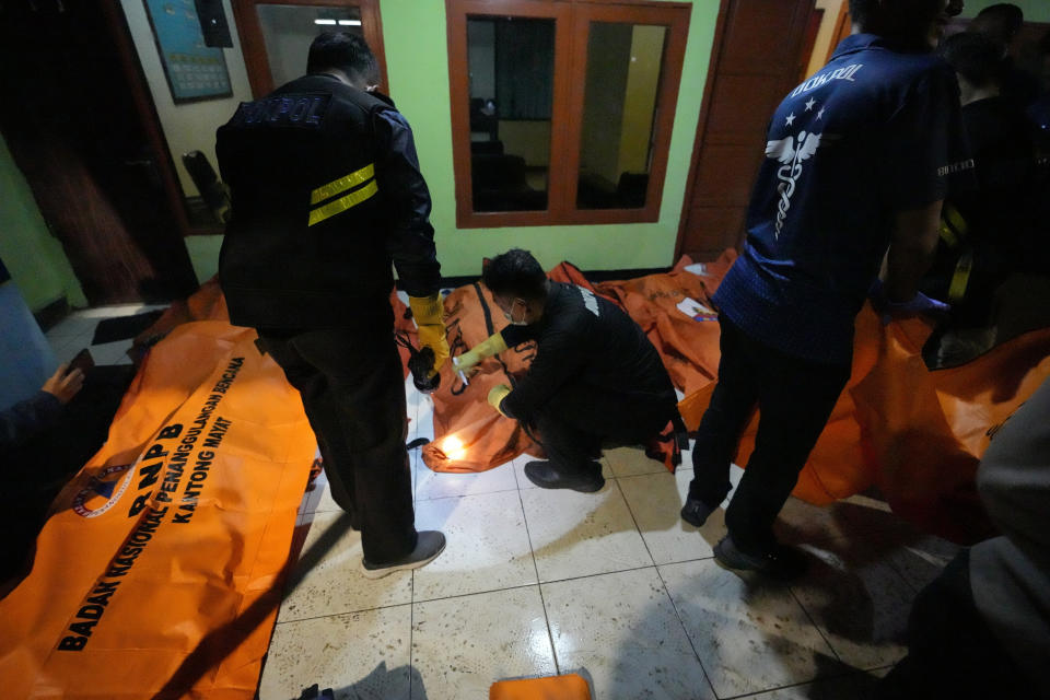 Indonesian police inspect the body bags of victims after a fire broke out at a neighborhood in Jakarta, Indonesia, Friday, March 3, 2023. A large fire broke out at a fuel storage depot in Indonesia's capital on Friday, killing several people, injuring dozens of others and forcing the evacuation of thousands of nearby residents after spreading to their neighborhood, officials said. (AP Photo/Achmad Ibrahim)