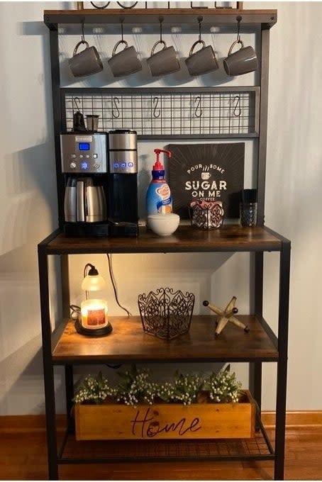 a reviewer photo of the rack used as a coffee station with a machine, cups, sweeteners, and decorative items