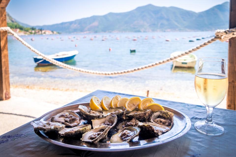 Oysters in a white plate with lemon and a glass of wine in Kotor, Montenegro