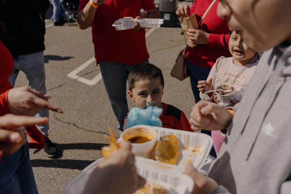 A family enjoying food from the vendors with a boy eating cotton candy in the center.