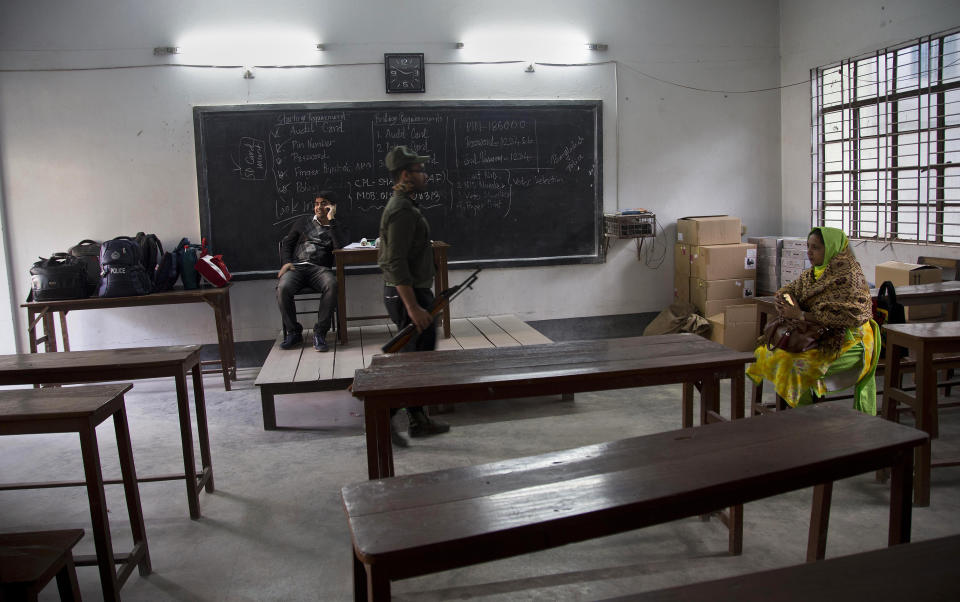 A Bangladeshi security personal stands guard as polling officials take rest after reaching a polling station on the eve of the general elections in Dhaka, Bangladesh, Saturday, Dec. 29, 2018. As Bangladeshis get set for Sunday's parliamentary elections, there are fears that violence and intimidation could keep many away from the polls, including two opposition candidates who said police had barricaded them inside their homes. (AP Photo/Anupam Nath)