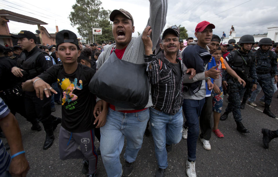 Honduran migrants walk past a roadblock of Guatemalan police as they make their way to the U.S., in Esquipulas, Guatemala, Monday, Oct. 15, 2018. Police stopped the migrants for several hours but the travelers refused to return to the border and were eventually allowed to pass. (AP Photo/Moises Castillo)