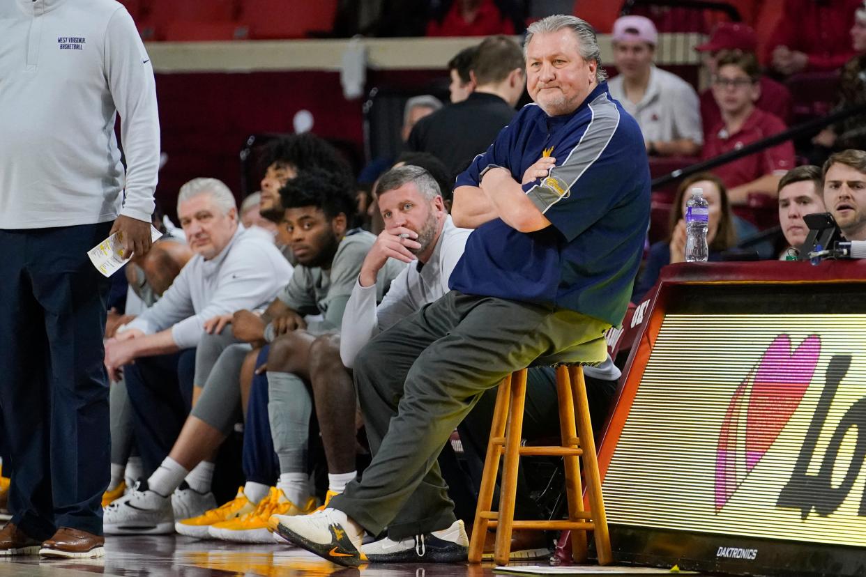 West Virginia head coach Bob Huggins, right, and Director of Basketball Operations Josh Eilert, center left, watch from the sidelines during the first half of an NCAA college basketball game against Oklahoma, March 1, 2022, in Norman, Okla.