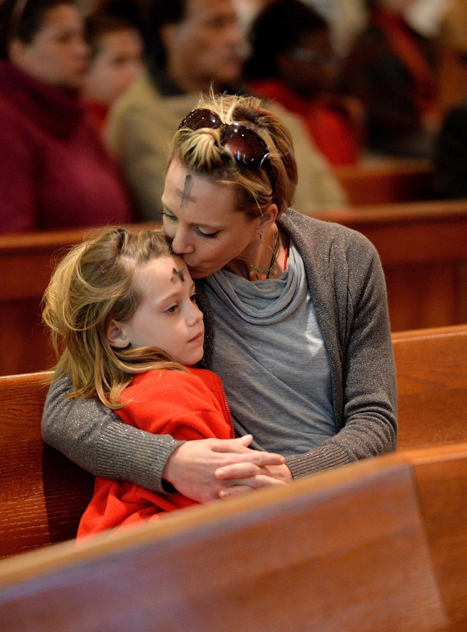 In this 2016 file photo, Marisa Zahariadis kisses her daughter Maggie on the head after receiving ashes at St. Matthew's Catholic Church in Jacksonville. This year Ash Wednesday and Valentine's Day fall on the same day.