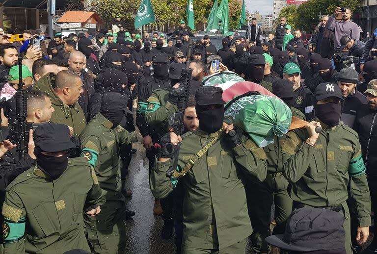 Hombres armados de Jamaa Islamiya llevan el cuerpo de su camarada Saeid al-Bashashi, quien fue asesinado en un aparente ataque israelí en Beirut el martes con uno de los principales comandantes de Hamas, Saleh al-Arouri, durante su cortejo fúnebre en la ciudad portuaria sureña de Sidón, Líbano, viernes 5 de enero de 2024. (AP Photo/Mohammed Zaatari)