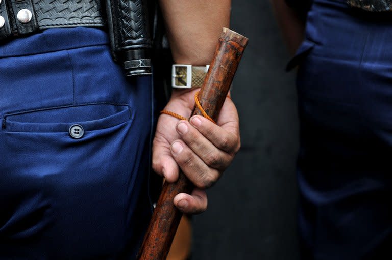 This file illustration photo shows a Philippine policeman holding his truncheon during a patrol in Manila, on March 20, 2012. A gunman shot dead three people and wounded several others when he opened fire in a crowded Philippine market on Friday, before he himself was shot dead, according to police