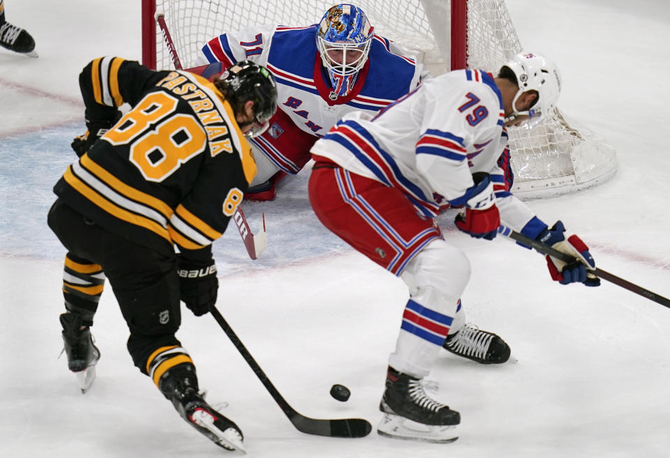 New York Rangers goaltender Keith Kinkaid, center, eyes the puck on a shot by Boston Bruins right wing David Pastrnak (88) during the first period of an NHL hockey game, Saturday, May 8, 2021, in Boston. At right is New York Rangers defenseman K'Andre Miller. (AP Photo/Charles Krupa)