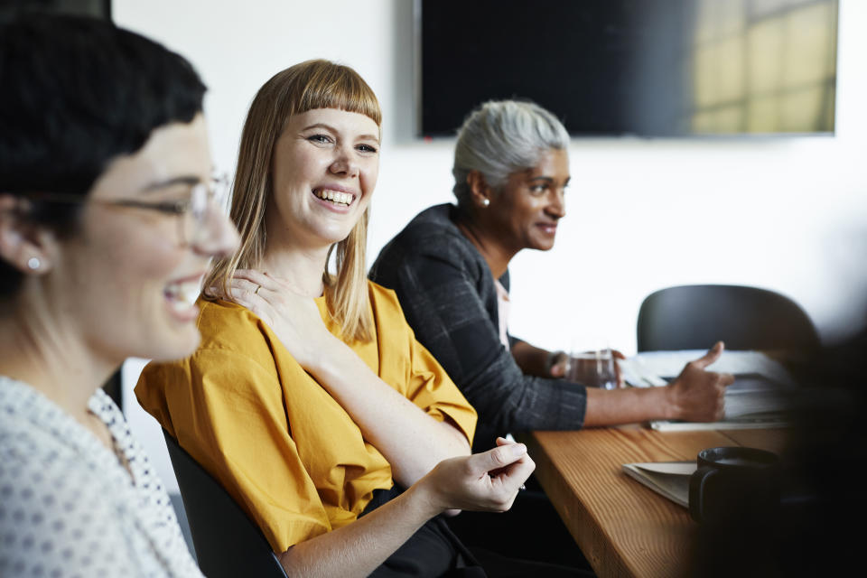 Smiling entrepreneur with female coworker looking away in meeting at workplace