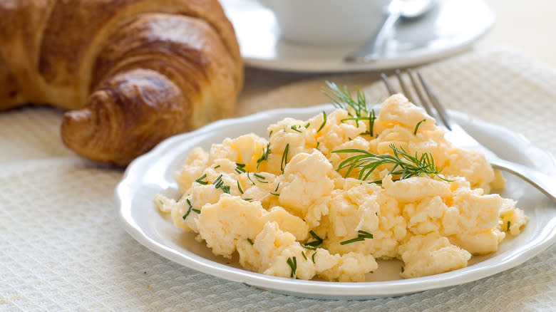 Scrambled eggs on plate with garnishments and bread
