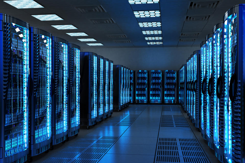 Interior of a blue-lighted data center showing stacks of servers in rows.