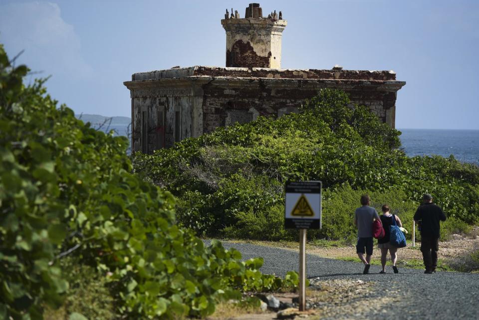 In this Jan. 13, 2017 photo, tourists walk toward Ferro Port lighthouse, at Verdiales Key point on the south coast of Vieques island, Puerto Rico. The tiny island long known for a former Navy bombing range is gradually working toward a different sort of boom: a growing tourist mecca. (AP Photo/Carlos Giusti)