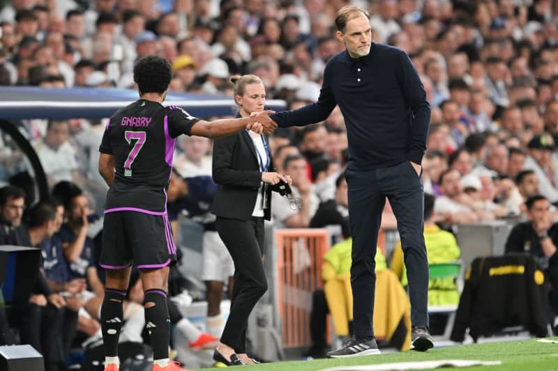Munich's Serge Gnabry (L) shakes hands with Munich's coach Thomas Tuchel during his substitution during the UEFA Champions League semi-final, second leg match between Real Madrid and Bayern Munich at the Santiago Bernabeu. Peter Kneffel/dpa