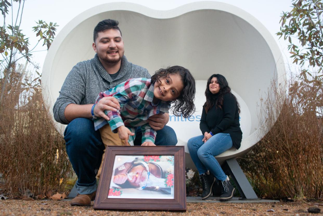 Abigail Quintero, right, husband Isidro Meixueiro, left, and their 4-year-old son, Antonio Meixueiro, middle, pose with a photo of their newest addition to their family, Ellieana Meixueiro, on Tuesday at the Ronald McDonald Foundation garden in Kansas City, Mo. Ellieana was born prematurely last month at the University of Kansas Medical Center in Kansas City, Kan. The family is seeking support to help cover the rising financial costs it is incurring.